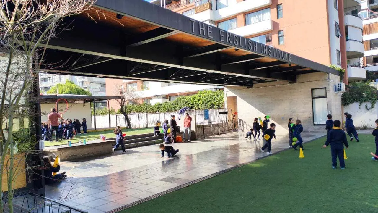 Niños pequeños del Colegio TEI jugando bajo un techo sobre pasto sintético