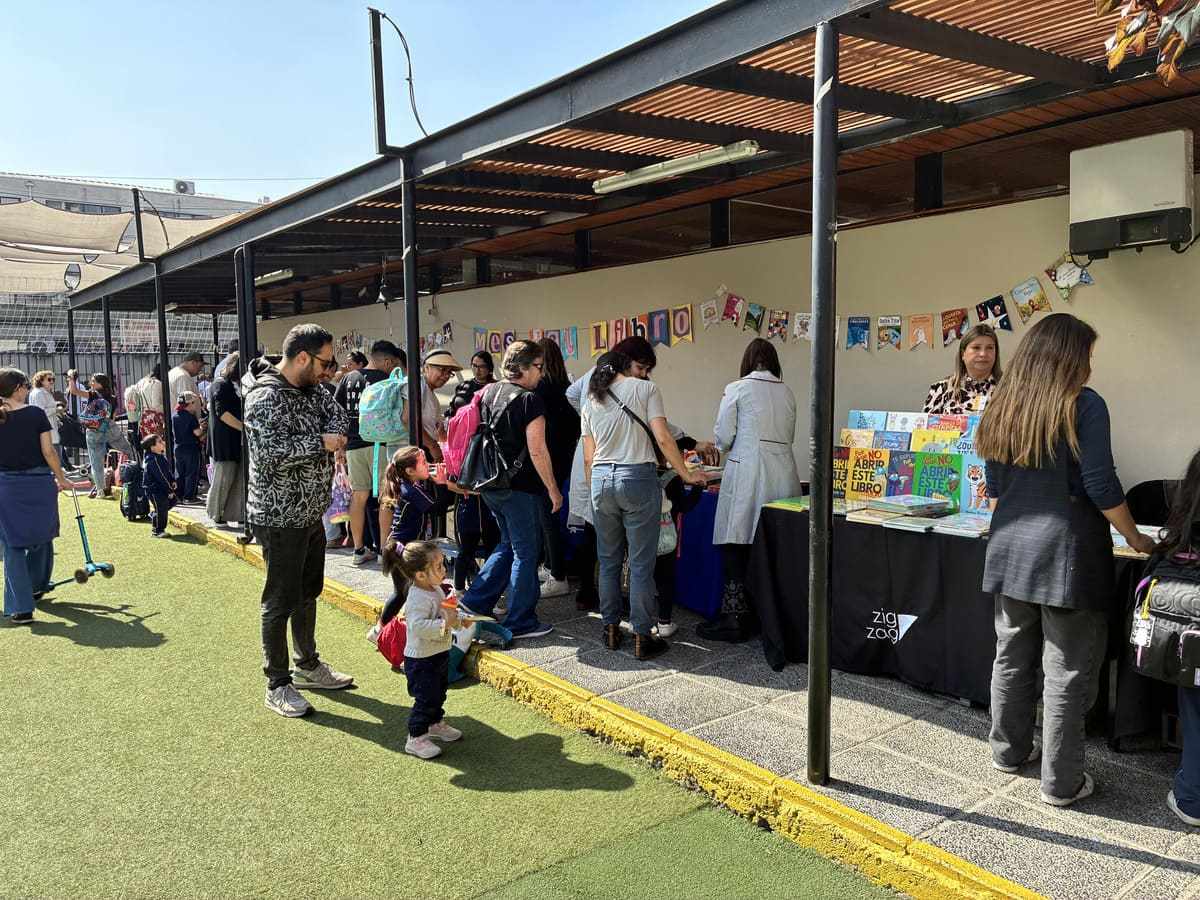 Familias del Colegio TEI recorriendo stands en una feria bajo el pasillo techado