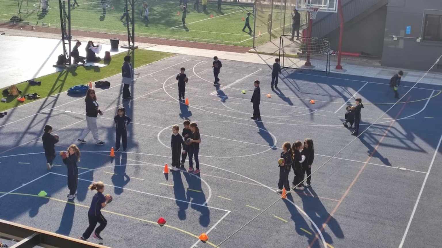 Estudiantes del Colegio TEI en actividad deportiva en la multicancha, con conos y balones