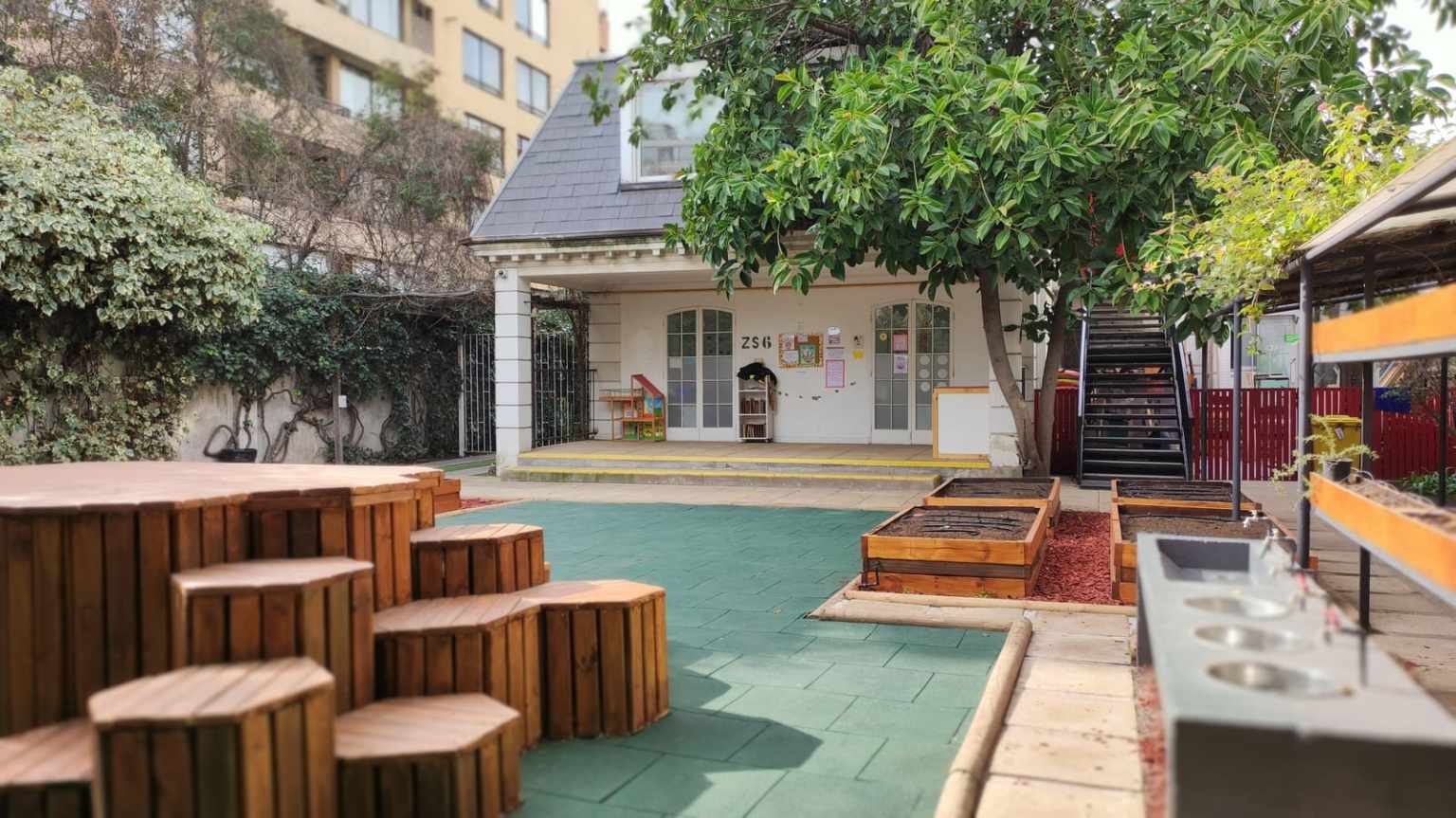 Patio de Early Years del Colegio TEI con asientos de madera, jardineras y juegos
