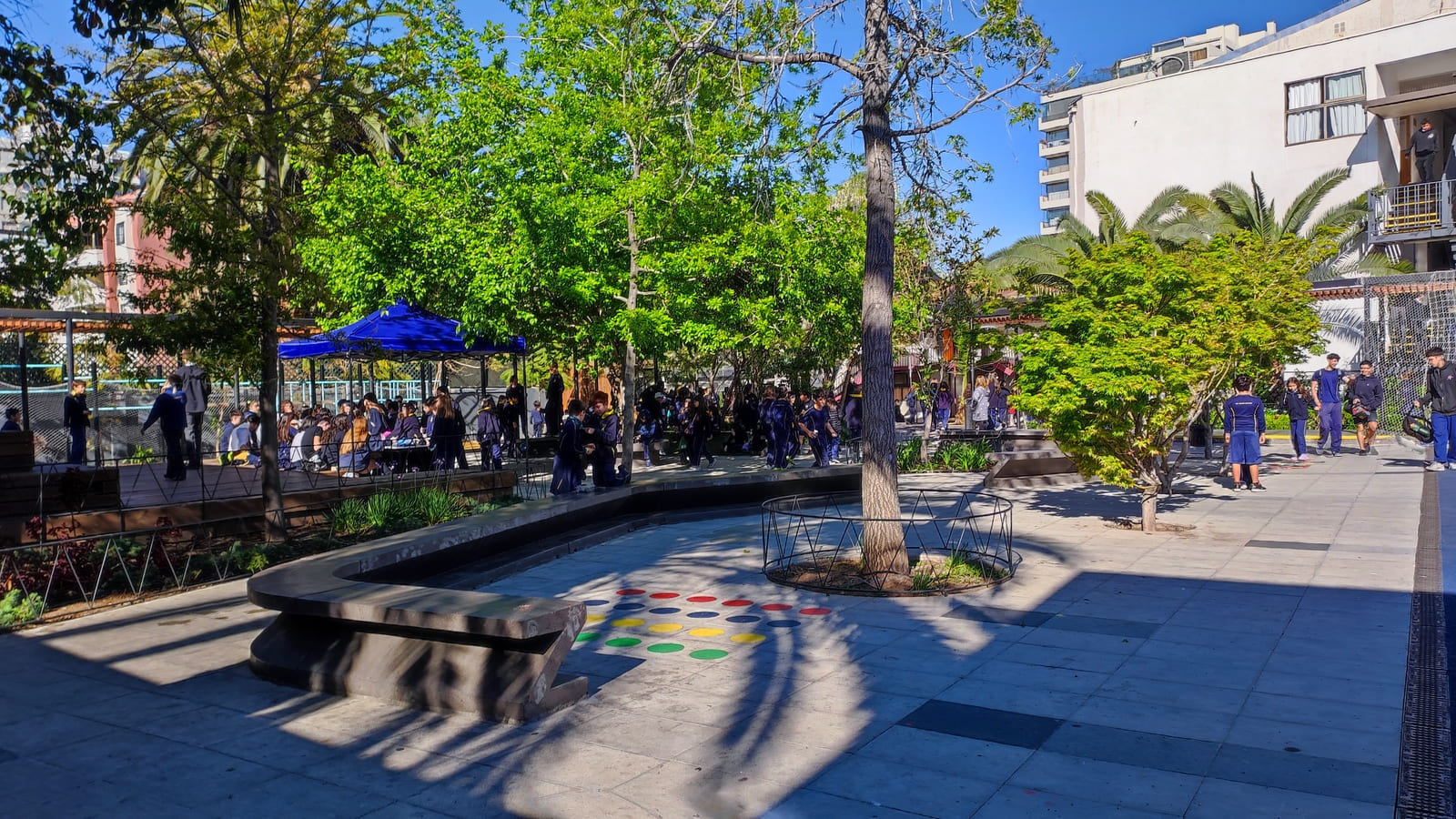 Patio central del Colegio TEI con árboles, bancas y estudiantes en recreo