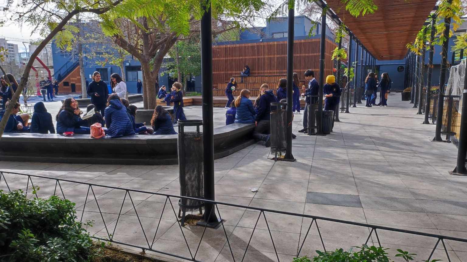Estudiantes del Colegio TEI conversando en el patio con árboles y pasillo techado