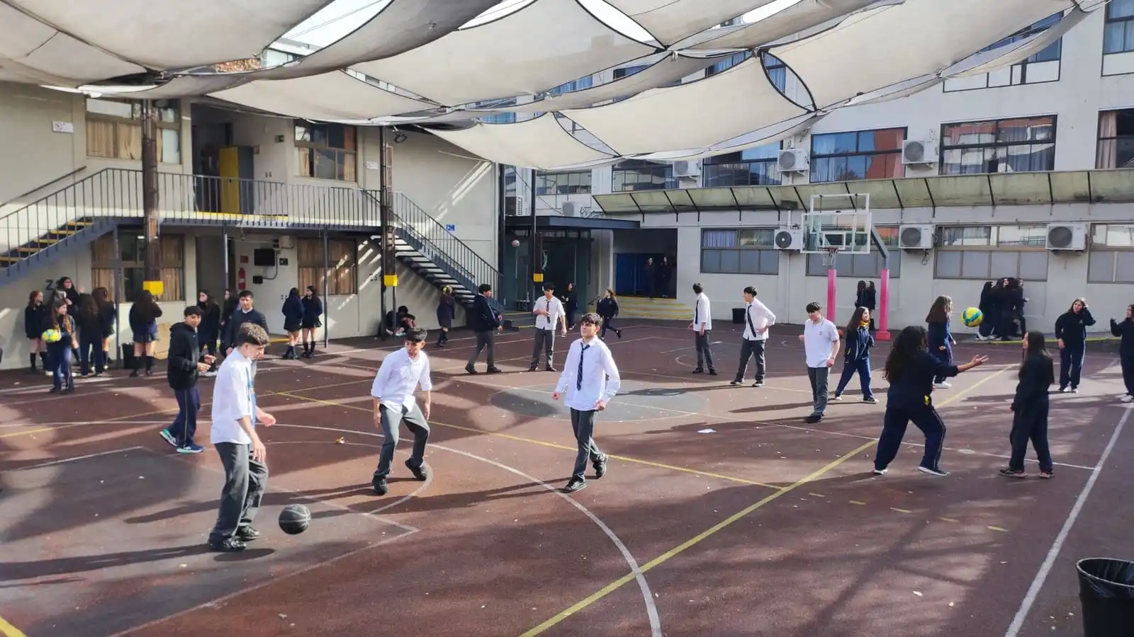 Estudiantes de Senior School del Colegio TEI jugando fútbol en el patio techado con toldos