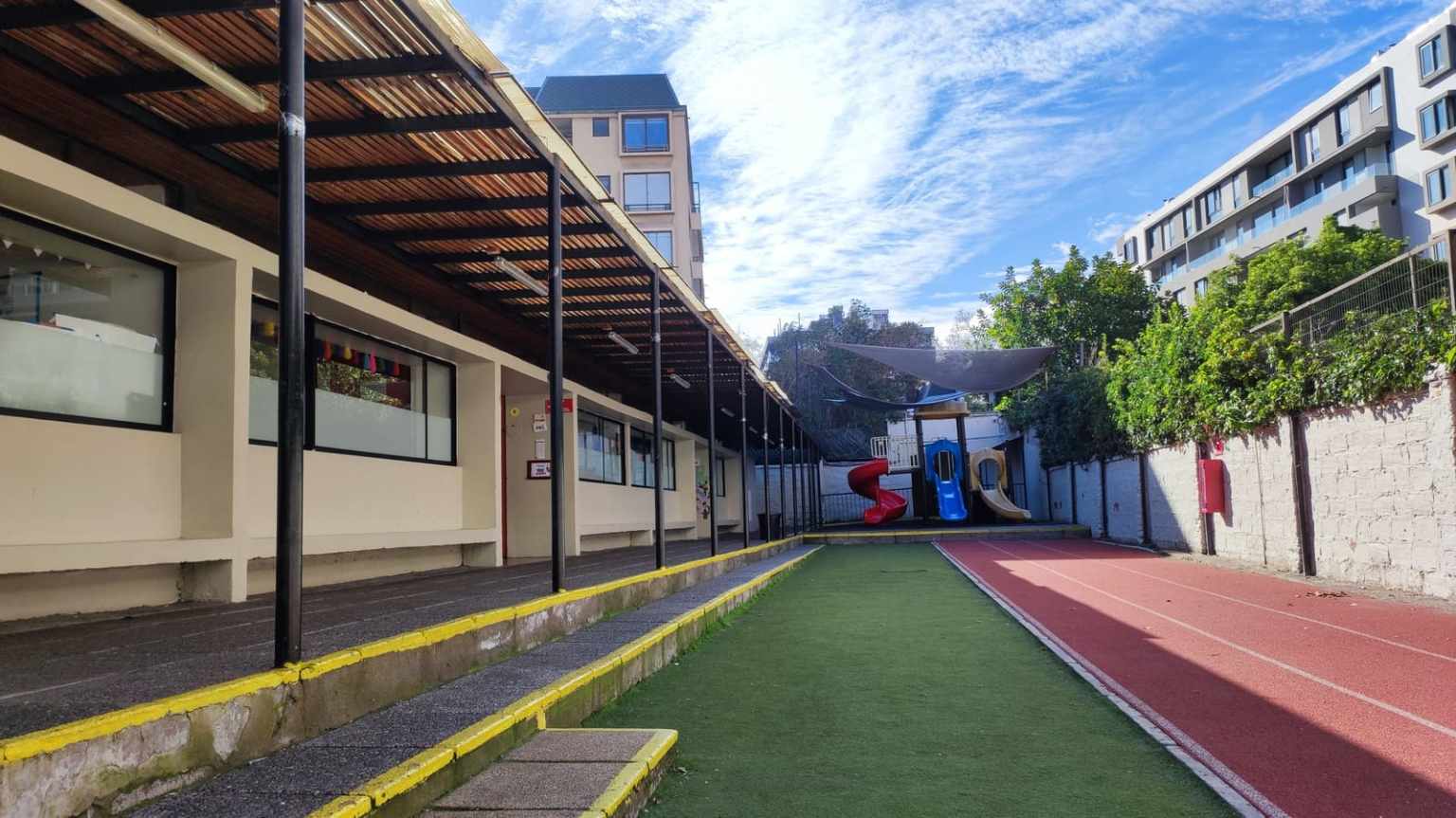 Pasillo techado, pasto sintético y pista atlética del sector de Junior School del Colegio TEI