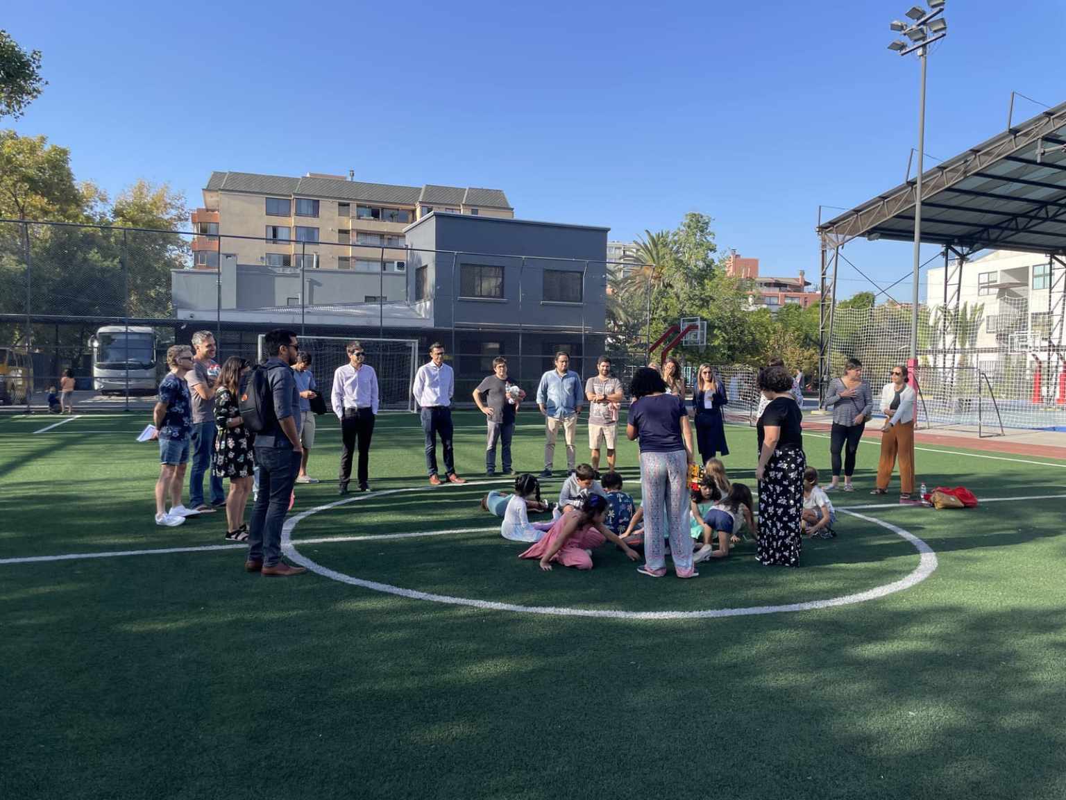 Adultos y niños del Colegio TEI participando en una actividad en la cancha de fútbol