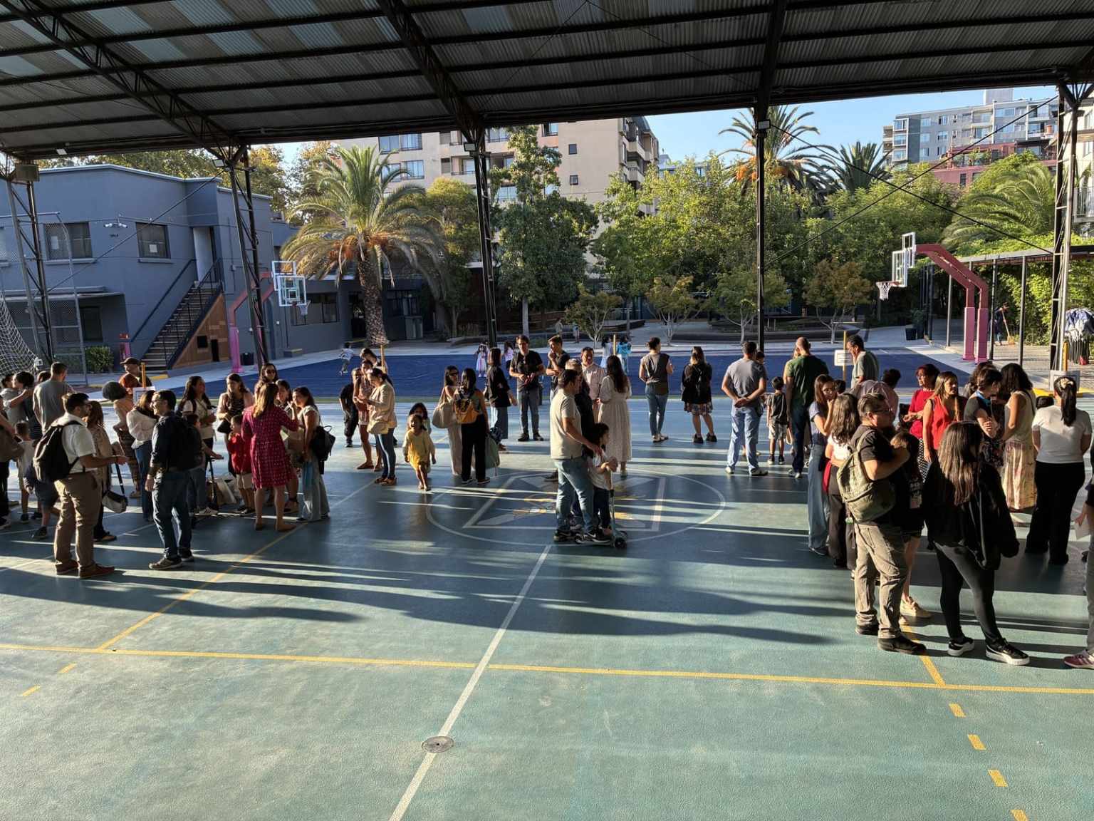 Familias y estudiantes del Colegio TEI reunidos en la multicancha durante una actividad