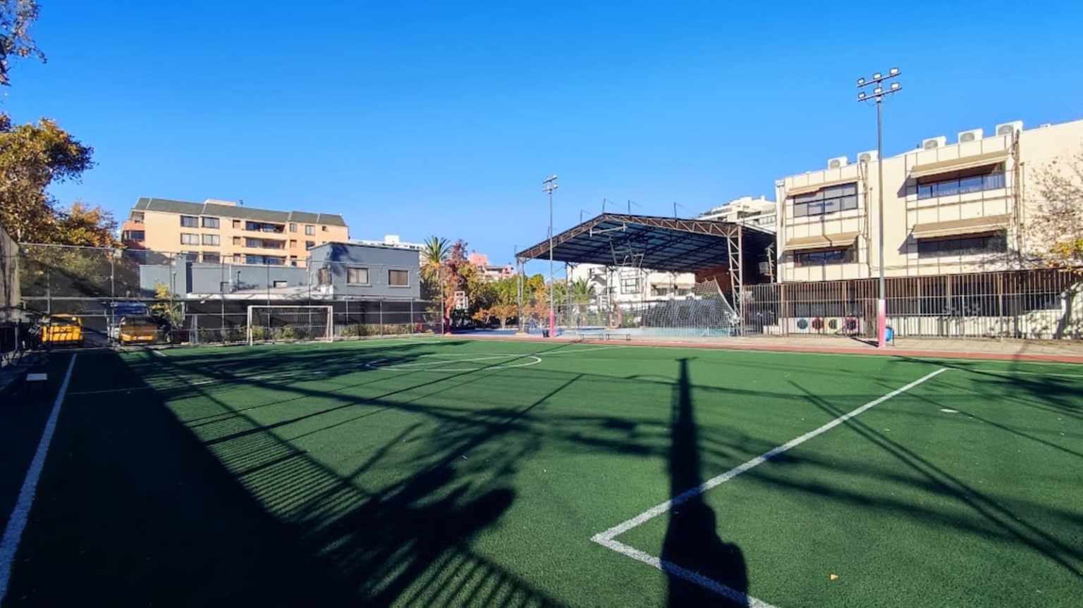 Cancha de fútbol de pasto sintético del Colegio TEI con arcos y un gimnasio techado al fondo